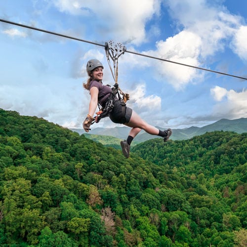Young woman zip lining above the trees