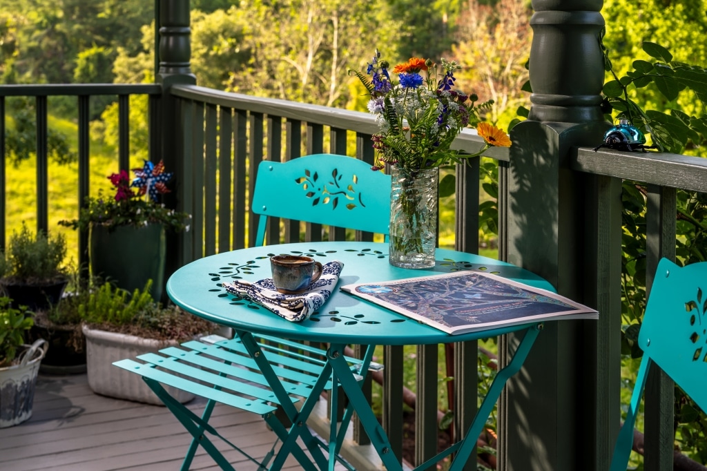 Coffee and wildflowers on a turquoise bistro table on the porch at Inn at Amaris Farms in Weaverville, NC