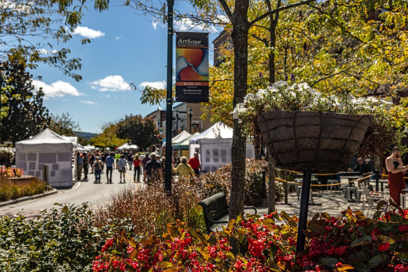 hendersonville-main-street-artscape Artist tents and shoppers along Main Street in Hendersonville with hanging flower baskets and fall color